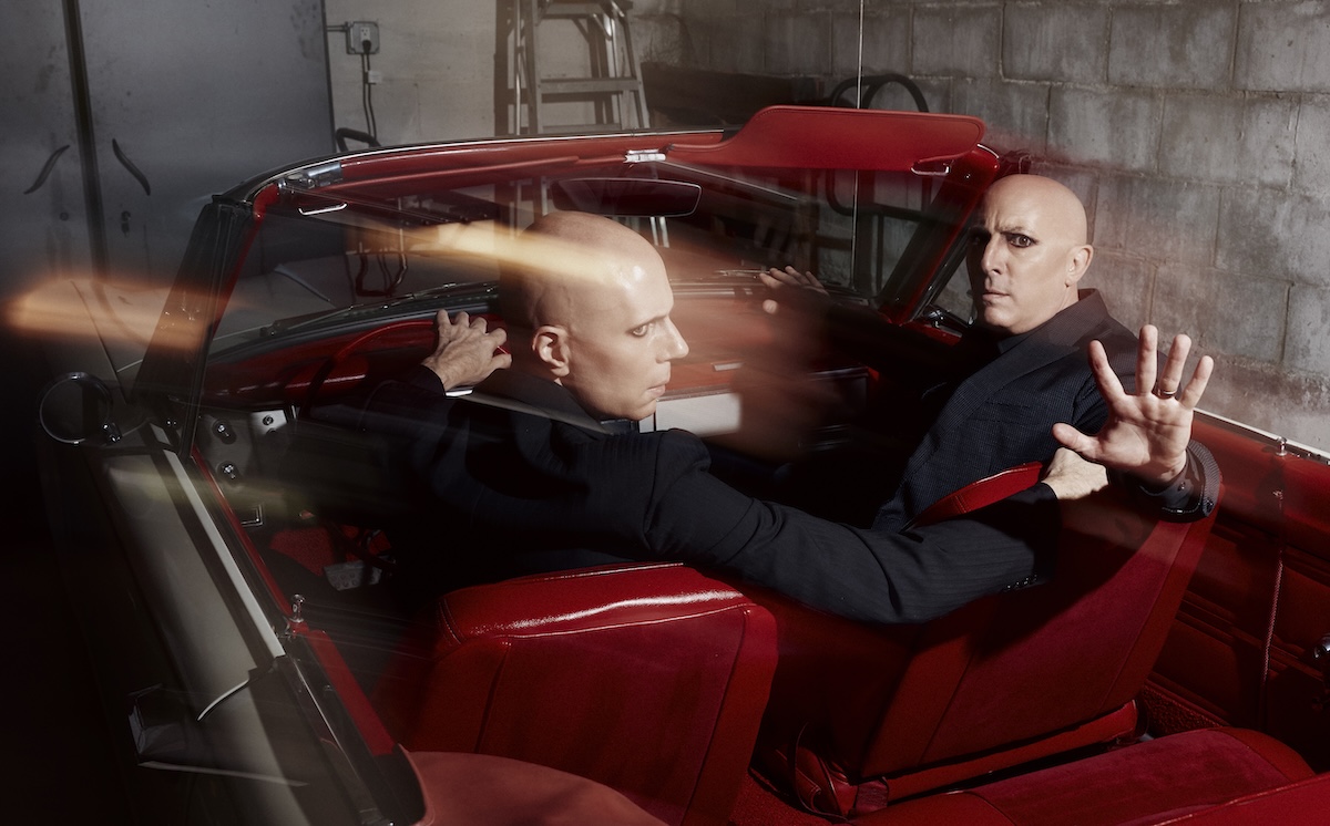 A Perfect Circle band members posing inside a vintage red convertible car, photo by Travis Shinn.